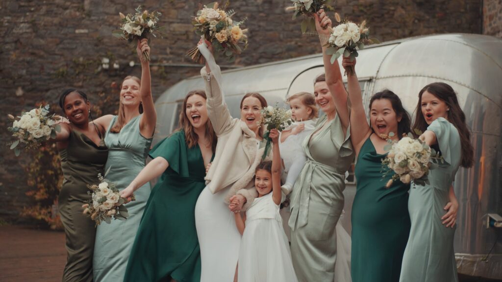 Bride and her group of bridesmaids pushing flowers into the air