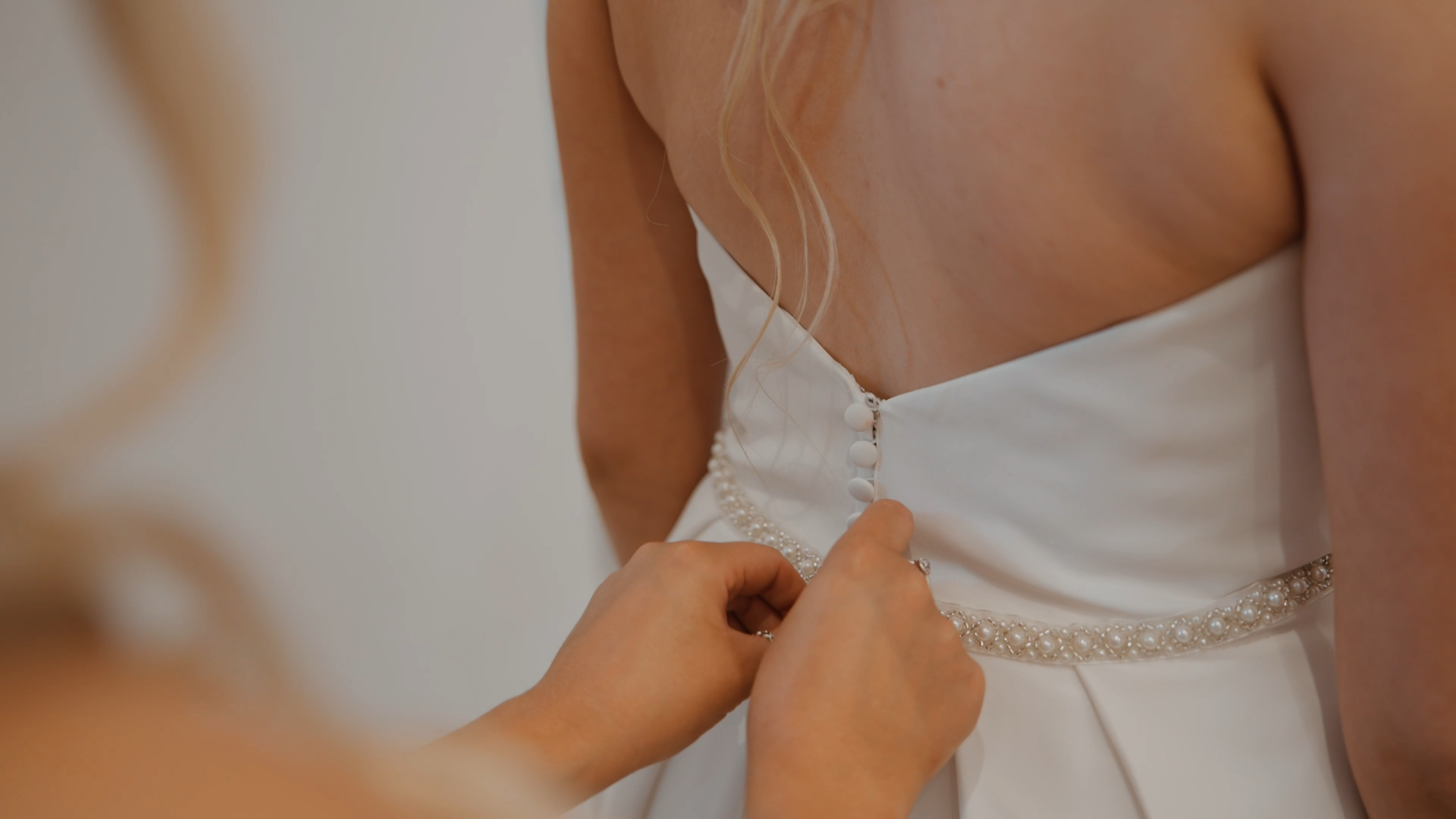 Close-up of a hand buttoning the bride’s dress — a timeless detail and one of the key moments to capture in your wedding video by a Somerset wedding videographer