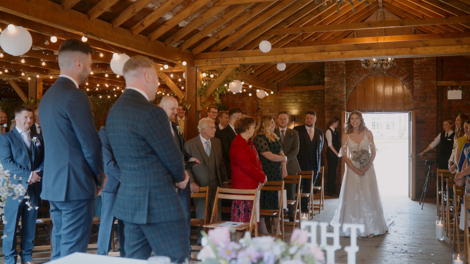  A wedding videographer captures a joyful night celebration as the groom pops champagne, with the bride and guests laughing amid the festive energy.