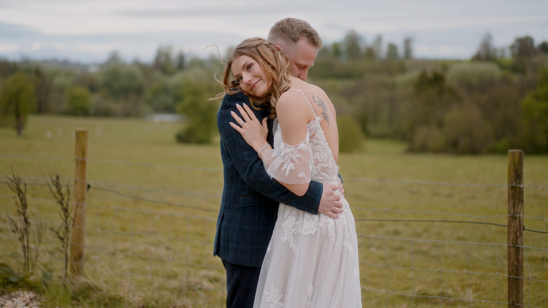 Bride and groom hugging in a vast Elhmay Park field, captured by a Somerset wedding videographer.