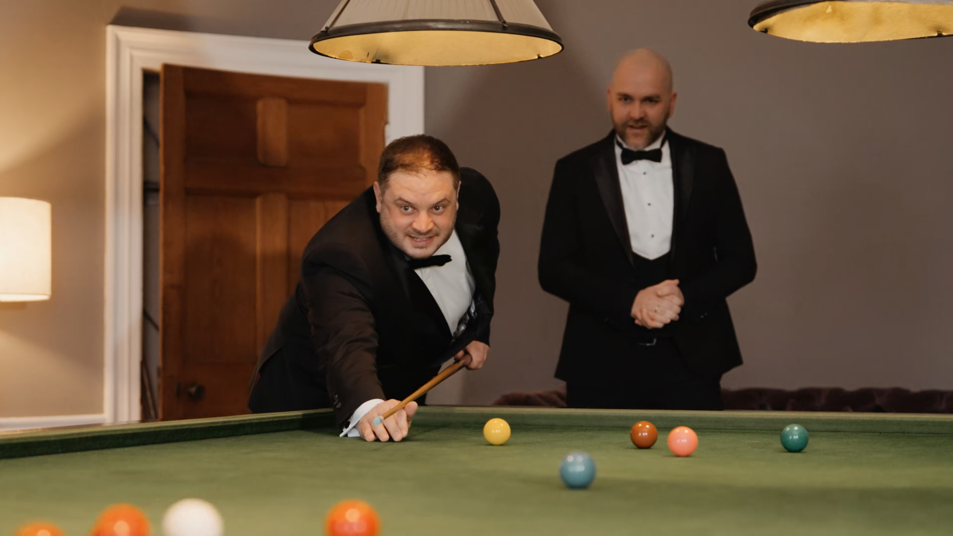 Groom wearing a stylish modern tuxedo, one of the standout wedding trends in 2025, casually playing billiards before the ceremony—capturing a relaxed yet fashion-forward pre-wedding moment.