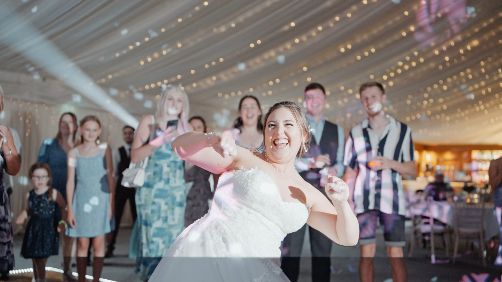 Bride dancing joyfully at her wedding, extending the celebration as one of the latest wedding trends in 2025, with guests smiling and enjoying the lively atmosphere around her.
