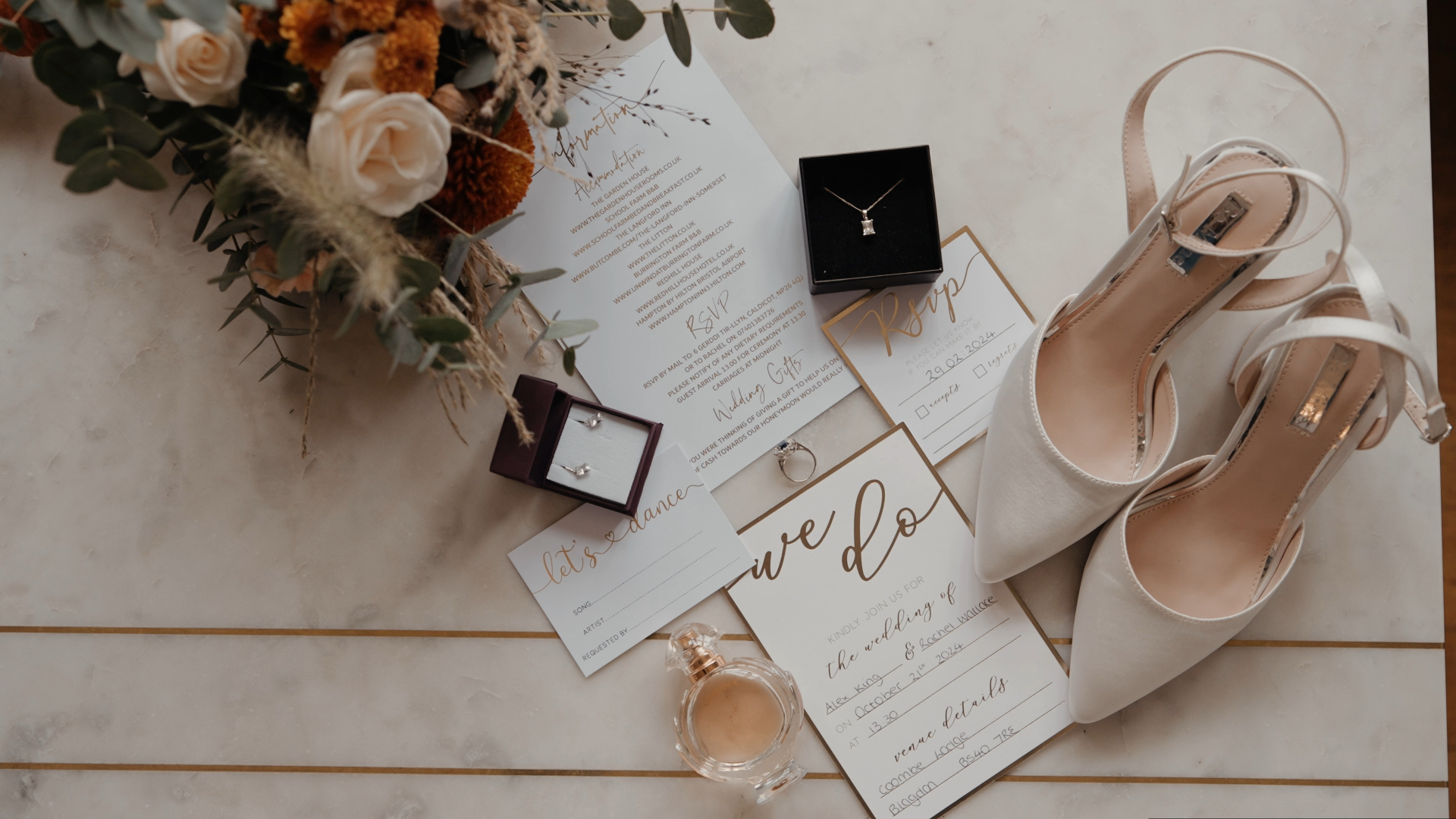 Artistic flat lay of bride’s heels, wedding invitation, rings, and a red and pink bouquet — a detailed shot by a documentary wedding videographer.