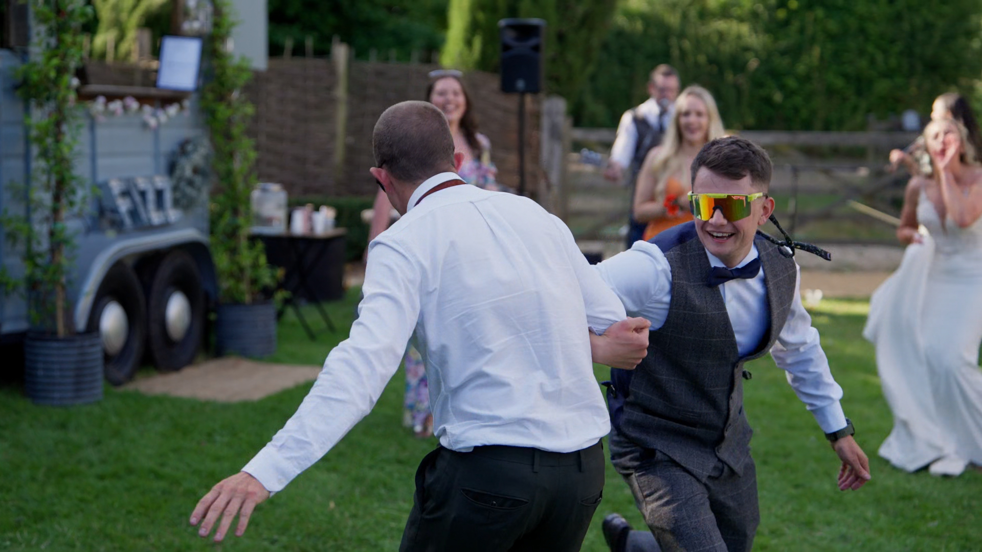 Candid moment of two male guests dancing with linked arms at the wedding reception.
