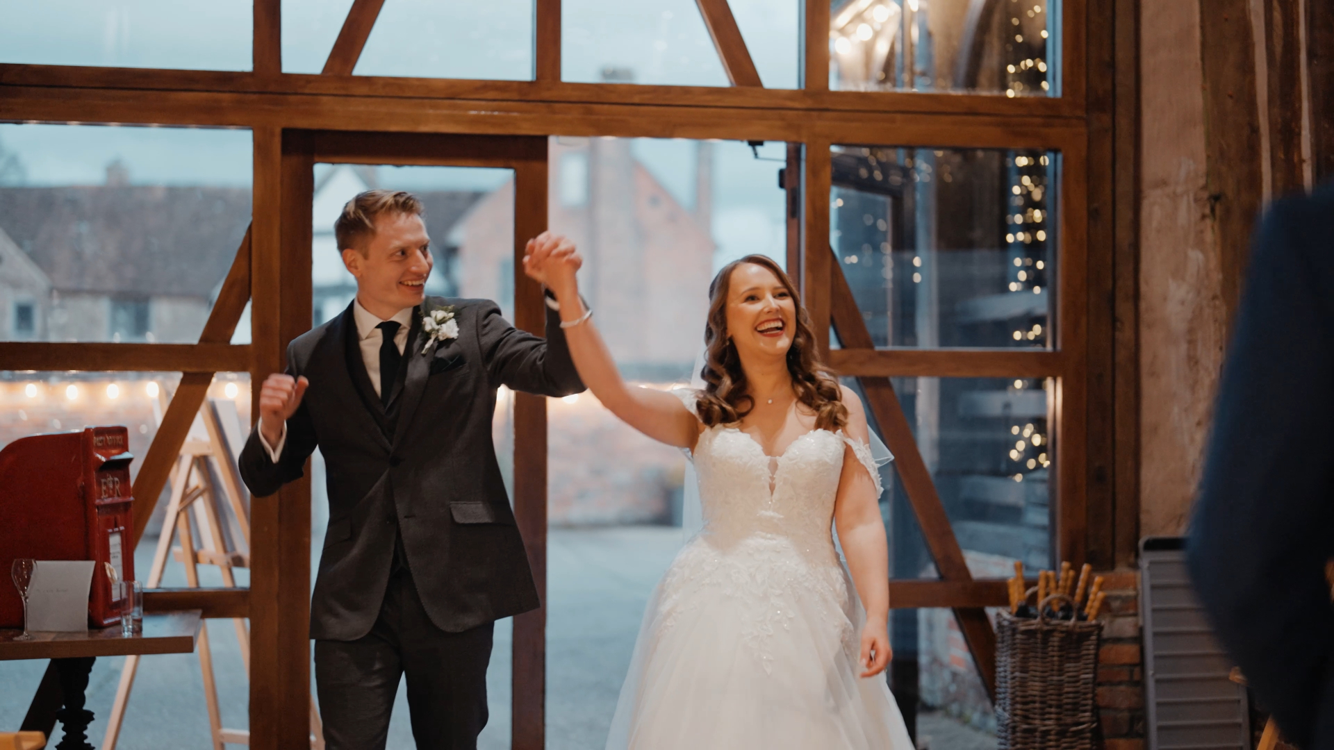 Bride and groom enter the reception area holding hands, with the groom raising their joined hands, captured in documentary style, reflecting a popular trend in 2025 wedding videography