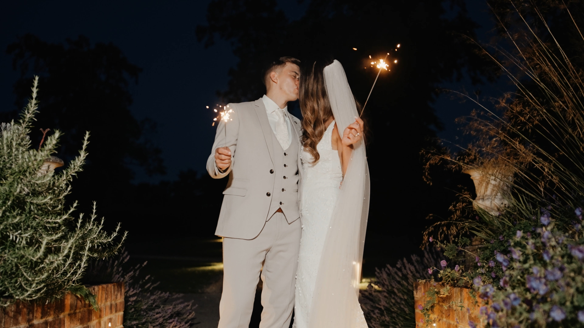 Bride and groom kissing while holding sparklers — a magical and cinematic moment to capture in your wedding video by a Somerset wedding videographer