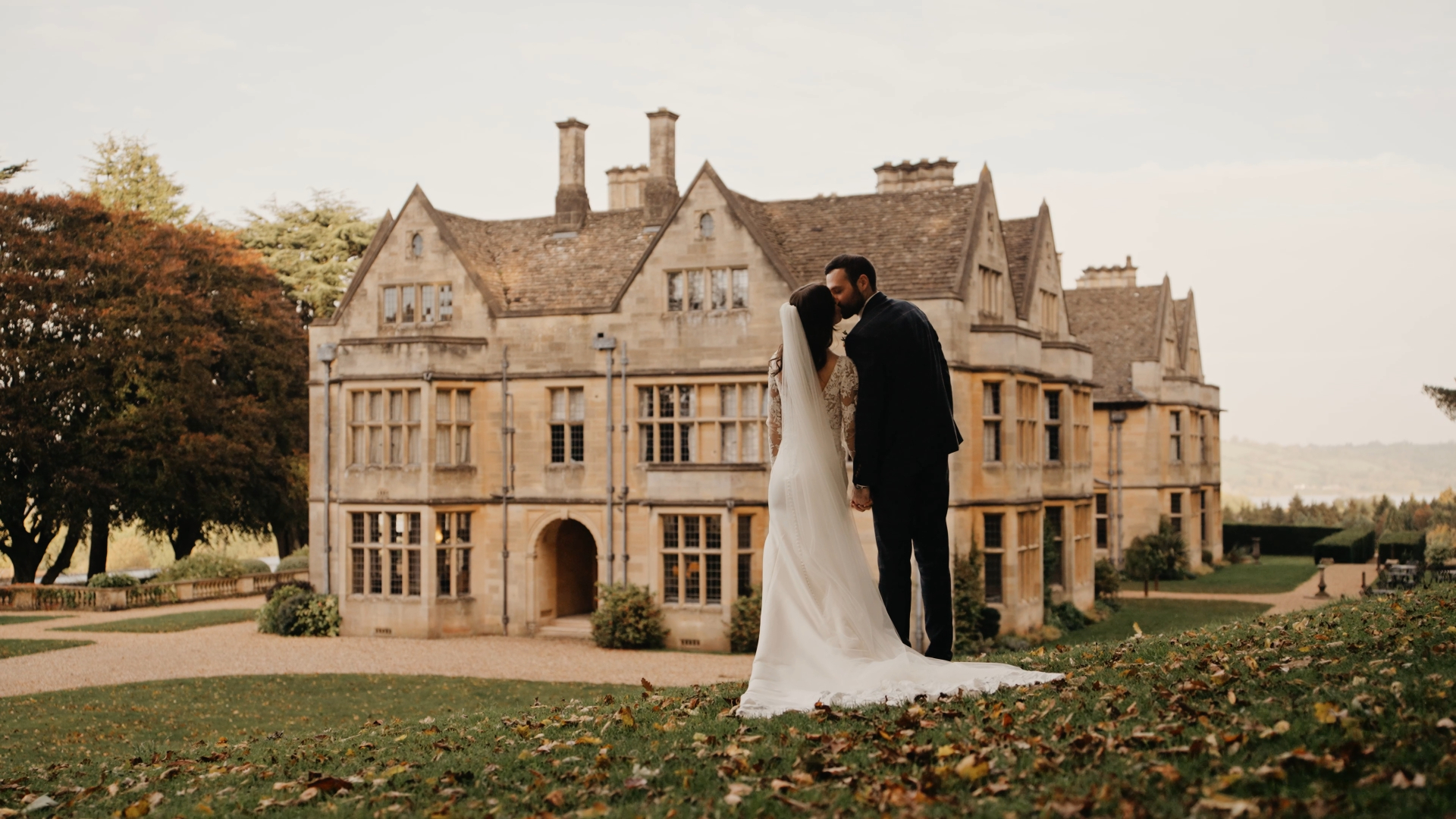 Bride and groom share a kiss in the lush garden outside Coombe Lodge, perfectly captured by a Somerset wedding videographer.