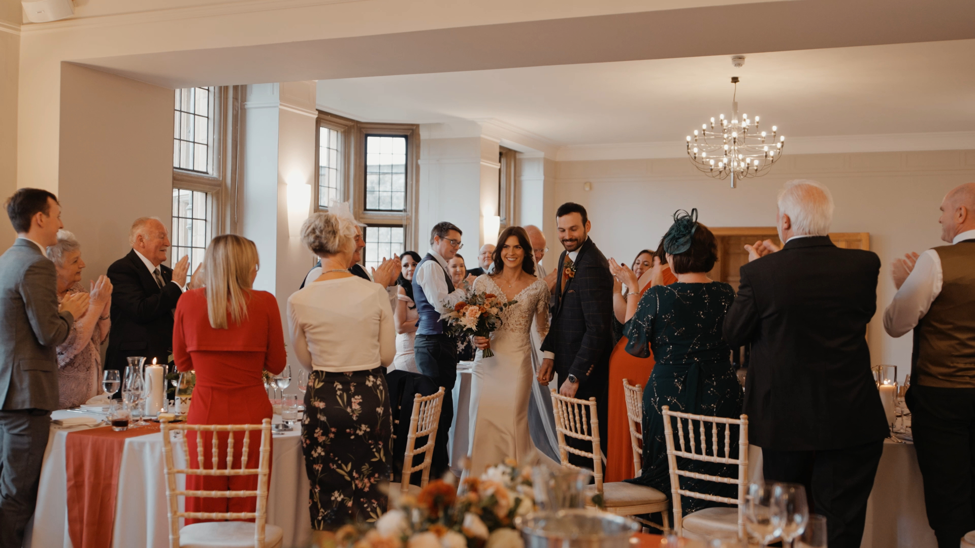 Bride and groom making their wedding breakfast entrance as guests clap and cheer — an energetic moment to capture in your wedding video by a Somerset wedding videographer