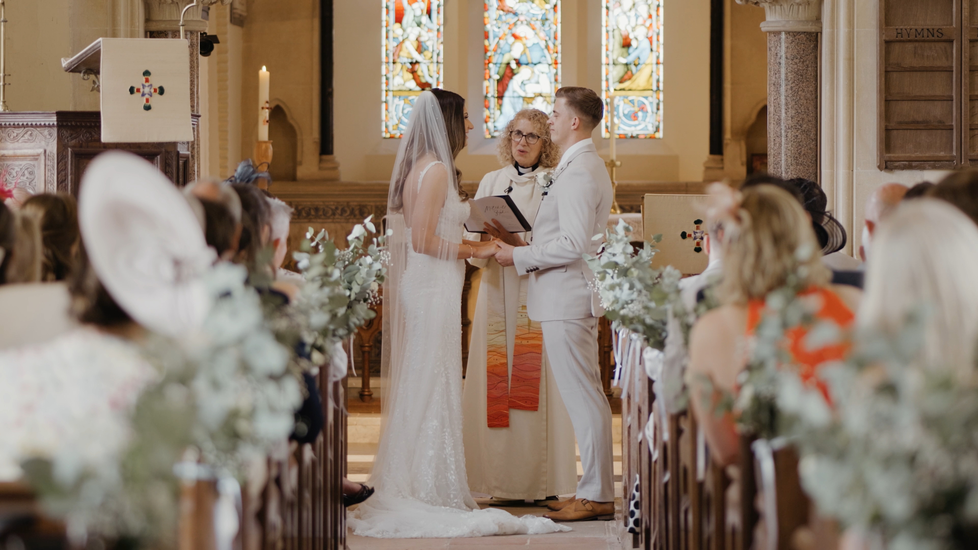 Bride and groom holding hands as officiant looks on during vow exchange — a heartfelt moment to capture in your wedding video by a Somerset wedding videographer