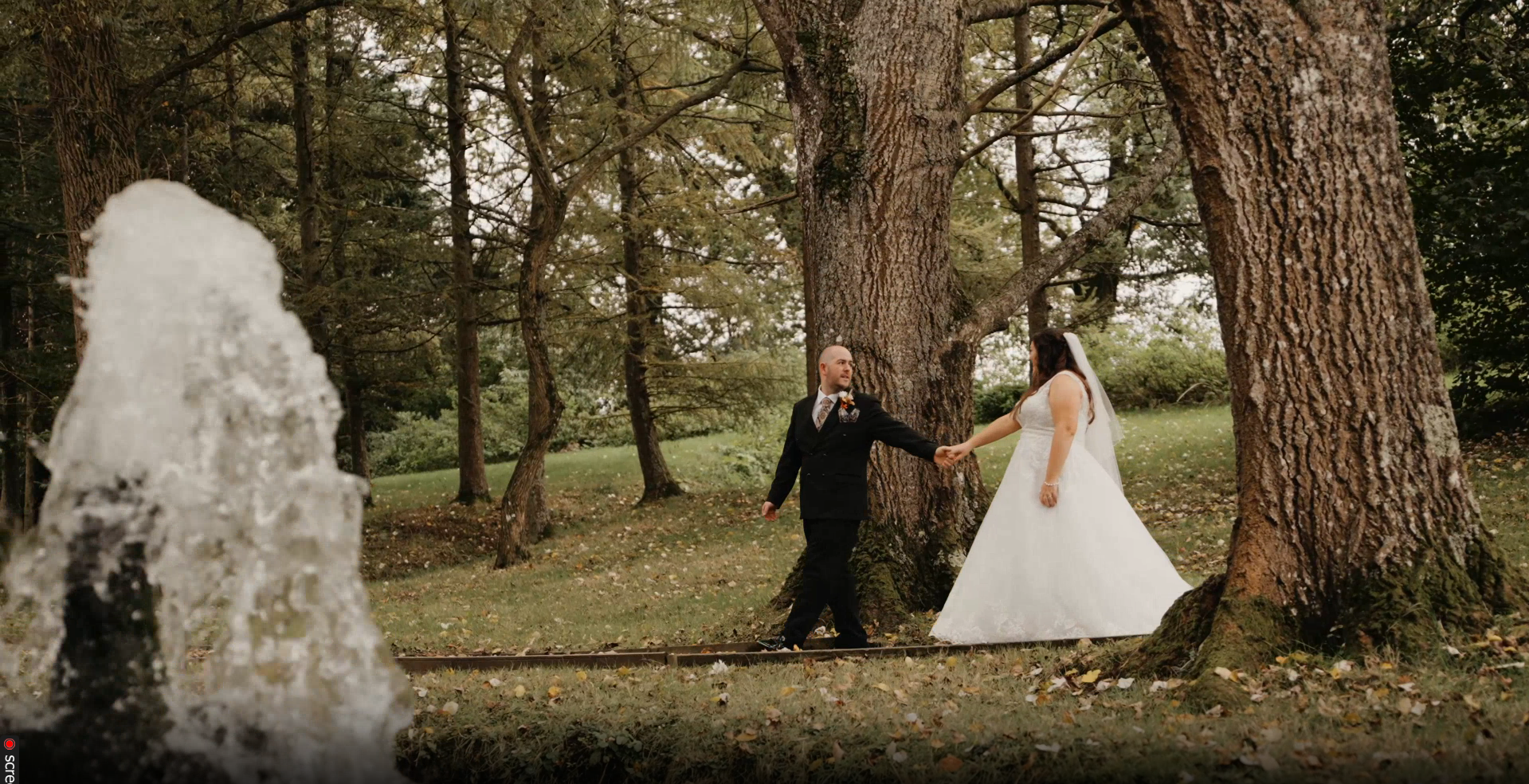 Bride and groom stroll through a forest at Hornsbury Mill, a magical moment captured by a Somerset wedding videographer.