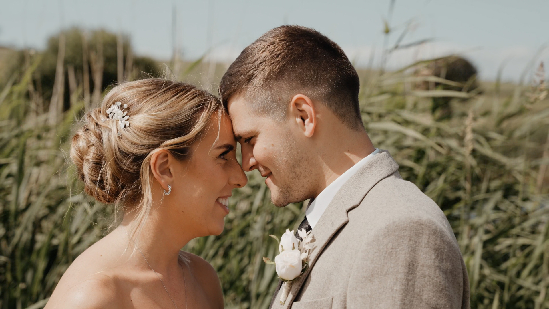 The bride and groom stand forehead to forehead, smiling warmly at each other, capturing a natural and flattering moment that shows how to look your best on camera.