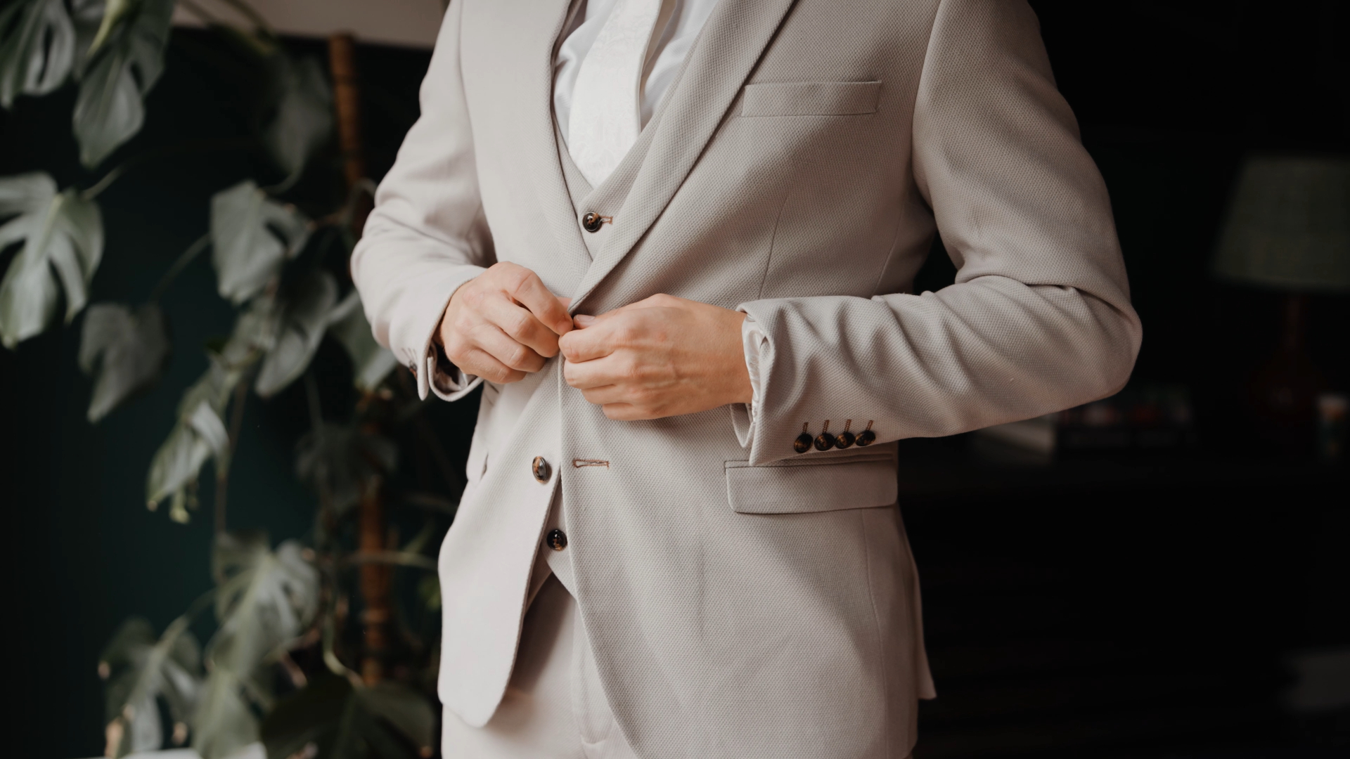 The groom buttoning his suit jacket with focus and poise, a classic preparation shot that highlights how to look your best on camera with confident posture and sharp styling.