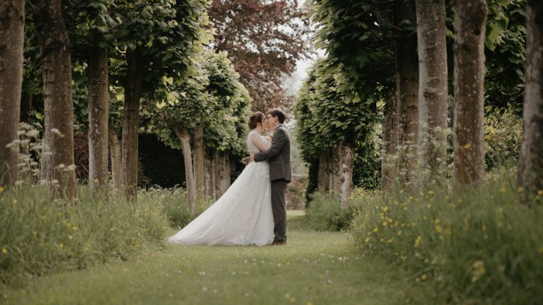A couple slow dancing in the middle of a lush forest in Somerset, surrounded by tall trees and soft, dappled sunlight filtering through the leaves, capturing a romantic elopement moment.