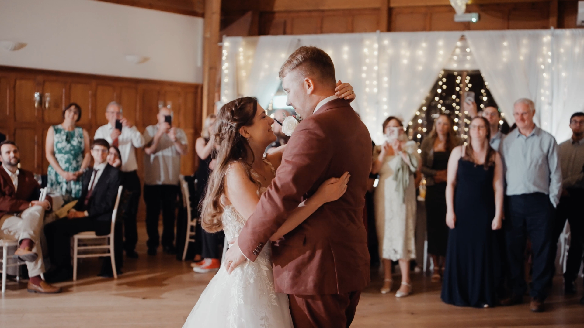 The bride and groom share their first dance, gazing into each other's eyes with timeless elegance, a perfect example of how to look your best on camera during emotional, candid moments.