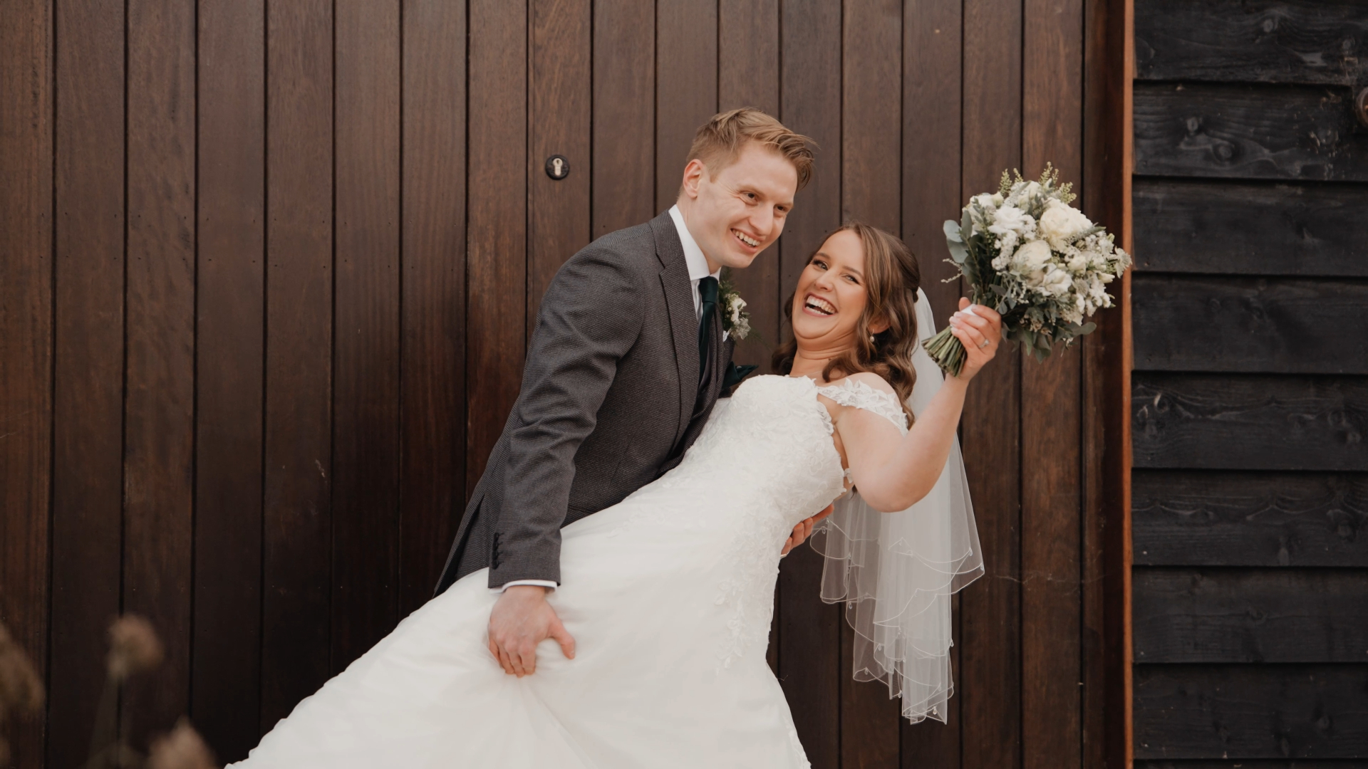 The groom dips the bride as they both smile happily at the camera, capturing a playful and romantic moment that shows how to look your best on camera during wedding portraits.