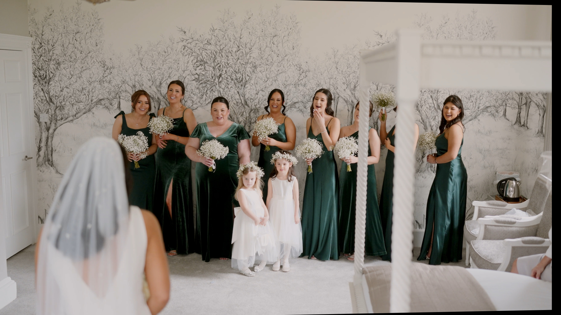 Bridesmaids and flower girls react with joy and emotion as they see the bride for the first time in her wedding dress, a touching moment beautifully documented by the Best Wedding Videographer in the South West.