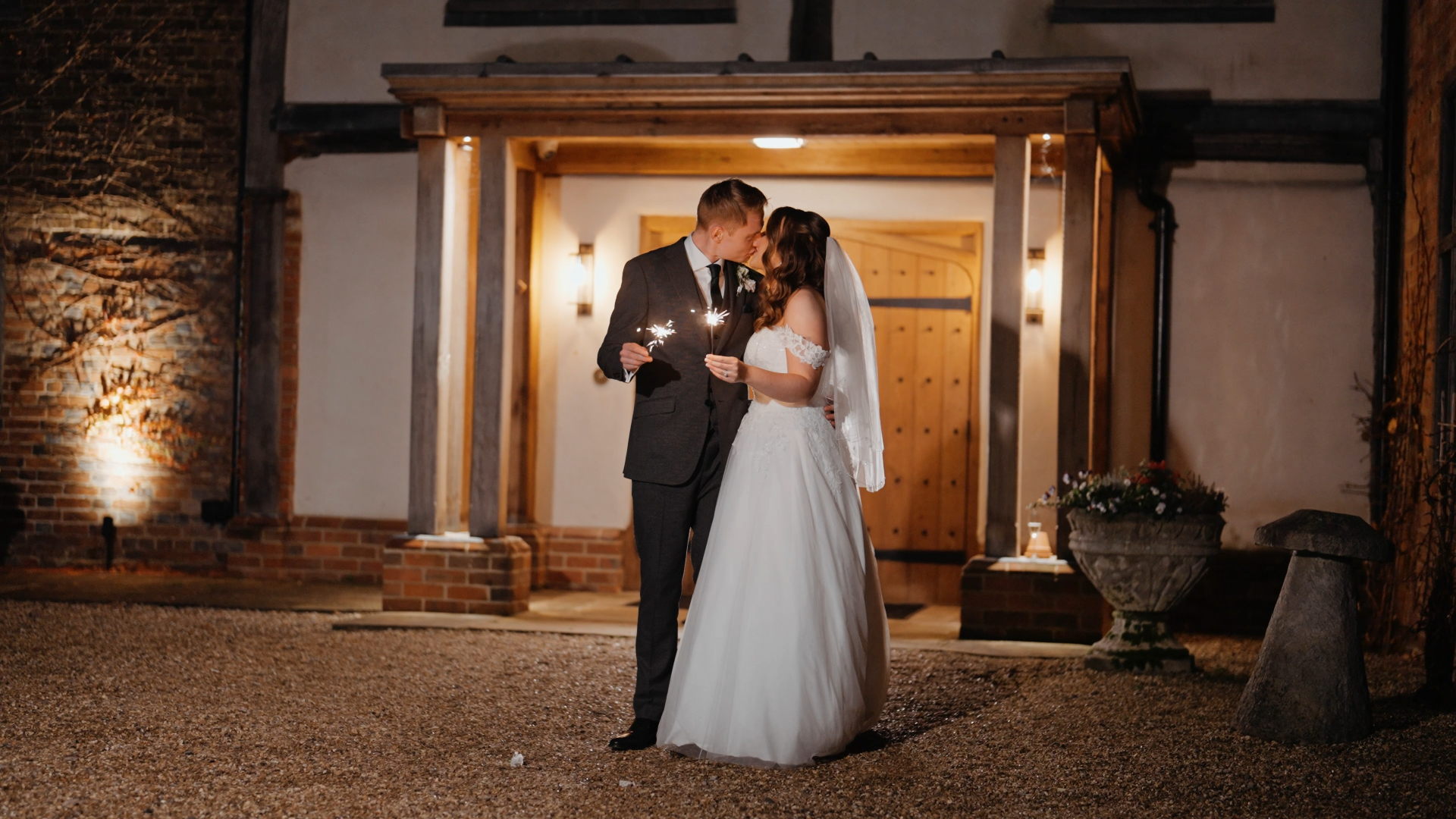 The bride and groom share a kiss while holding sparklers, creating a romantic and dazzling moment perfect for their wedding video.