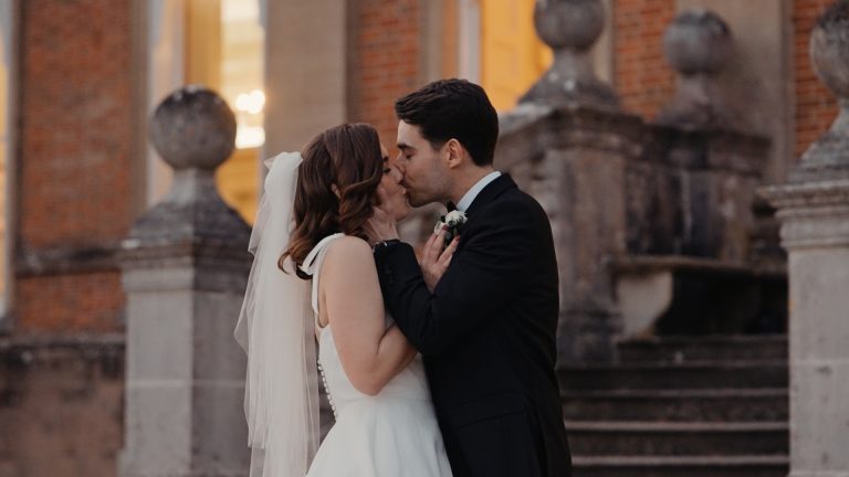 Groom kisses bride outside venue.