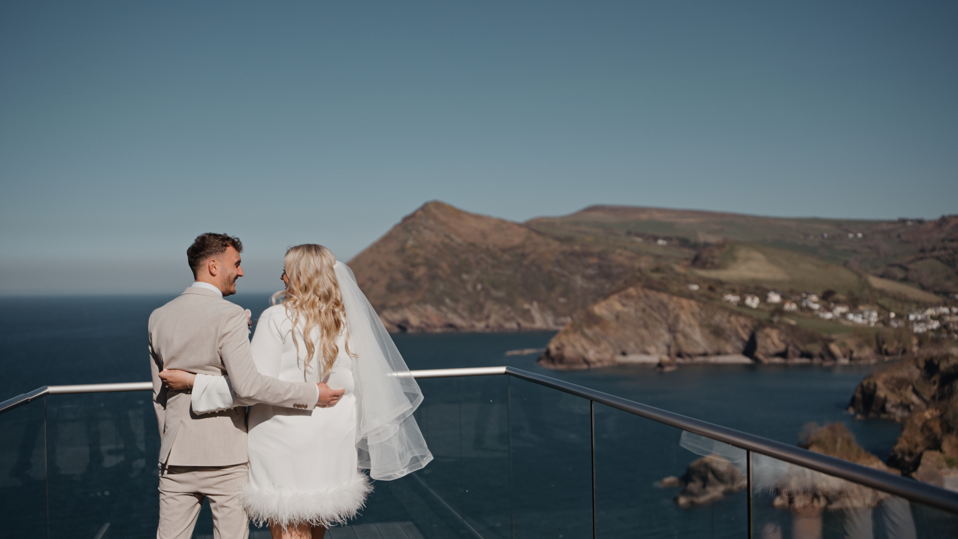 
The bride and groom standing side by side, looking out over a peaceful lake and scenic view, a serene and cinematic moment that can be negatively impacted by common wedding videography mistakes such as poor lighting or lack of composition.