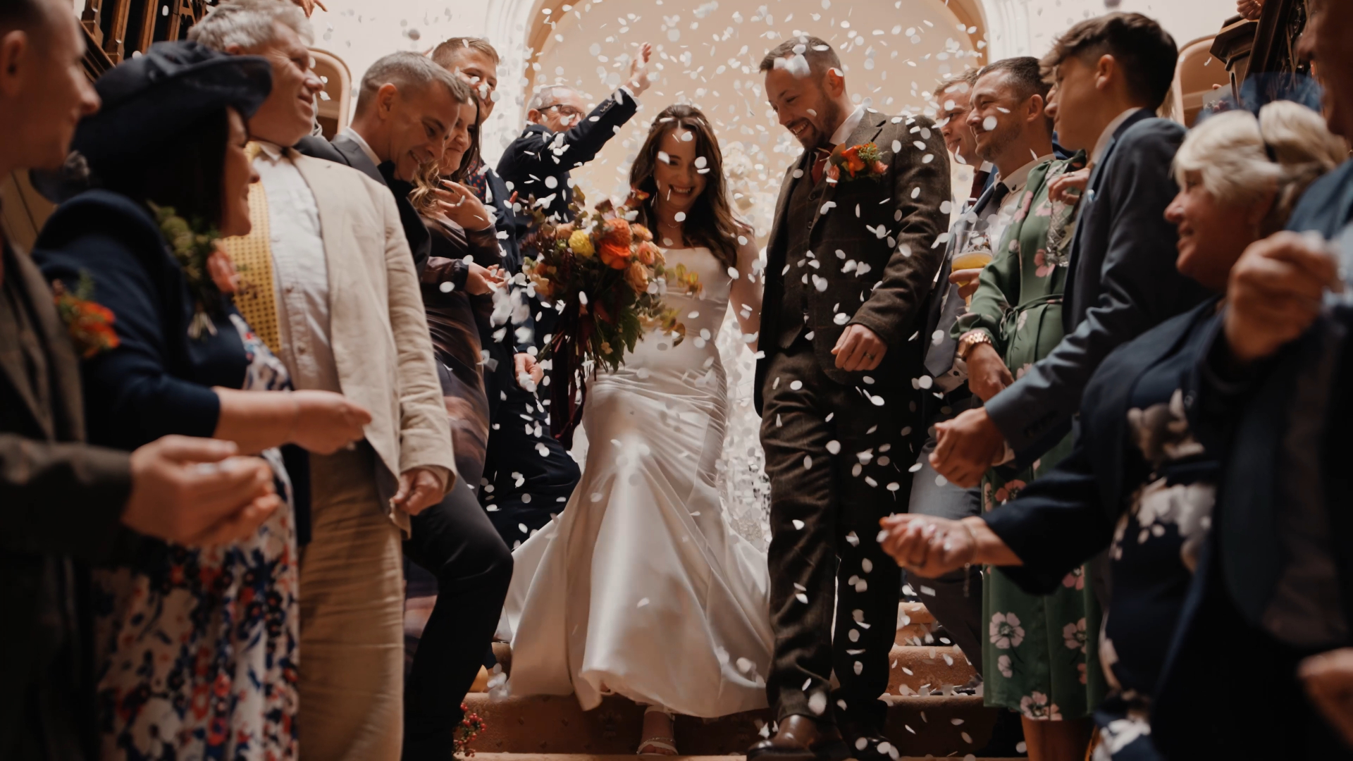 Guests throw flower petals at the bride and groom as they joyfully exit the wedding venue, a moment full of movement and emotion that can often be missed due to common wedding videography mistakes like poor timing or framing.