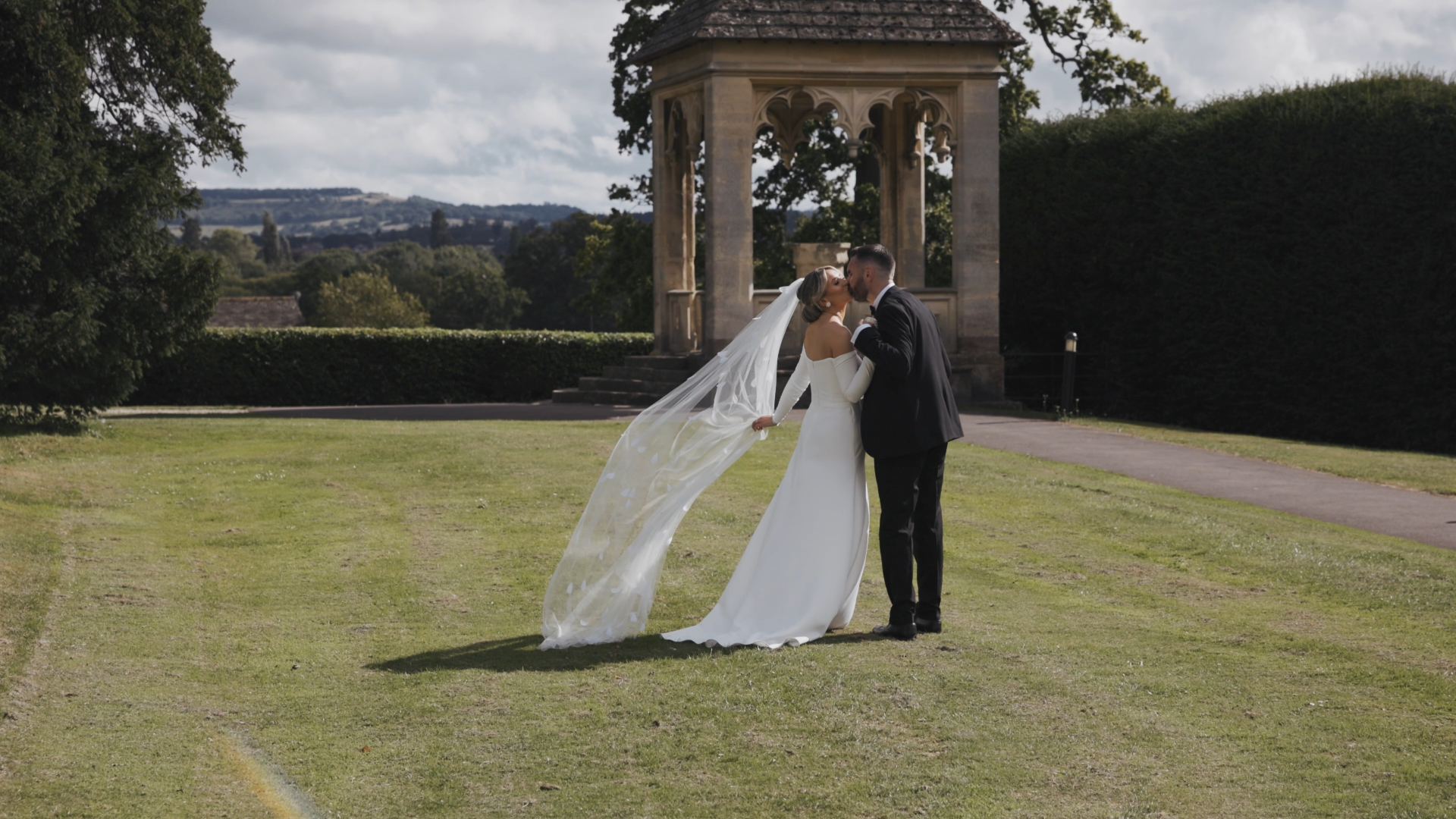 The bride and groom share a romantic kiss in the middle of a lush garden, a picture-perfect scene captured by the Best Wedding Videographer in the South West.