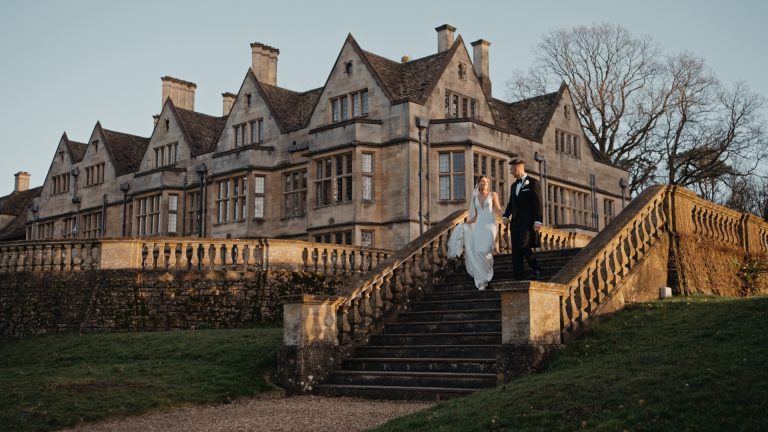 The bride and groom walking down the stairs outside Coombe Lodge, captured by the wedding videographer to document their joyful exit and the beautiful surroundings.