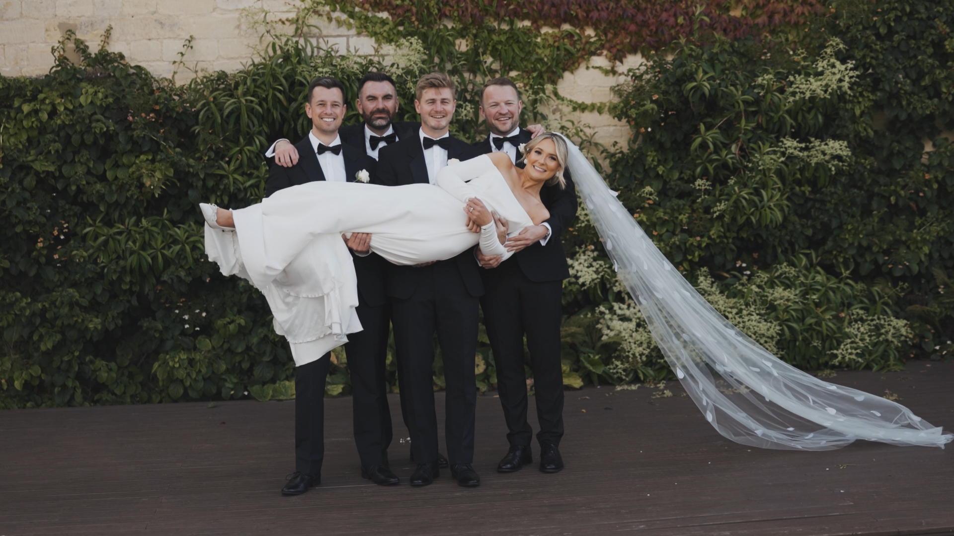 The groomsmen playfully carry the bride while everyone laughs, creating a fun and memorable moment perfectly captured by the Best Wedding Videographer in the South West.