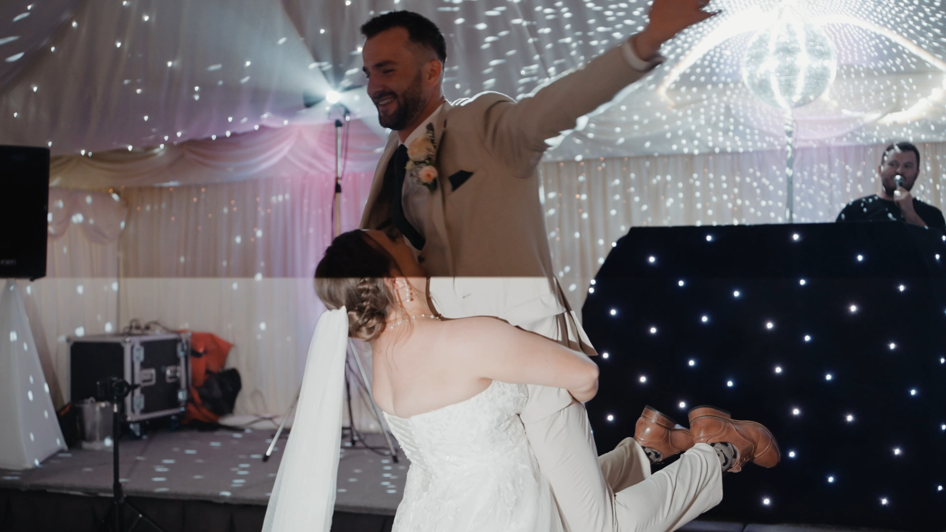 The bride carries the groom in her arms during their first dance, a playful and romantic moment captured by the wedding videographer.

