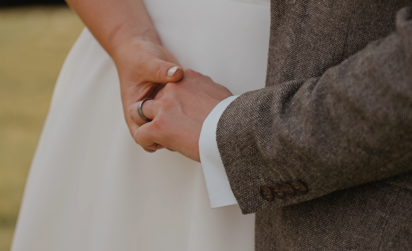Close-up of bride and groom holding hands, showing their wedding rings during a wedding at Priston Mill.