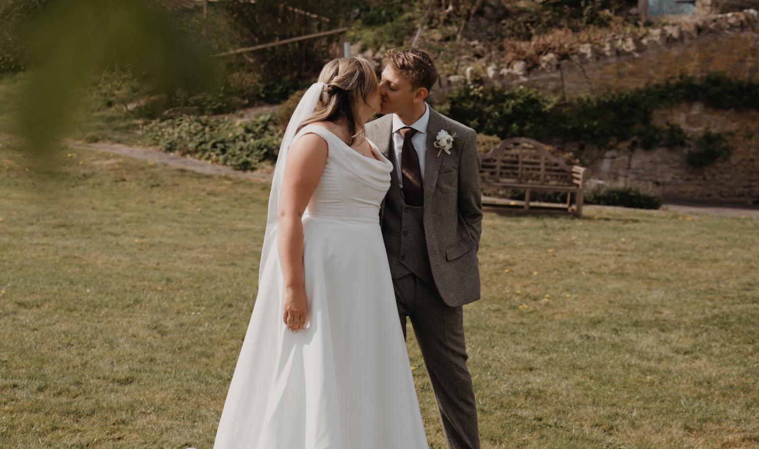  Bride and groom share a romantic kiss in the middle of a field during their wedding at Priston Mill.