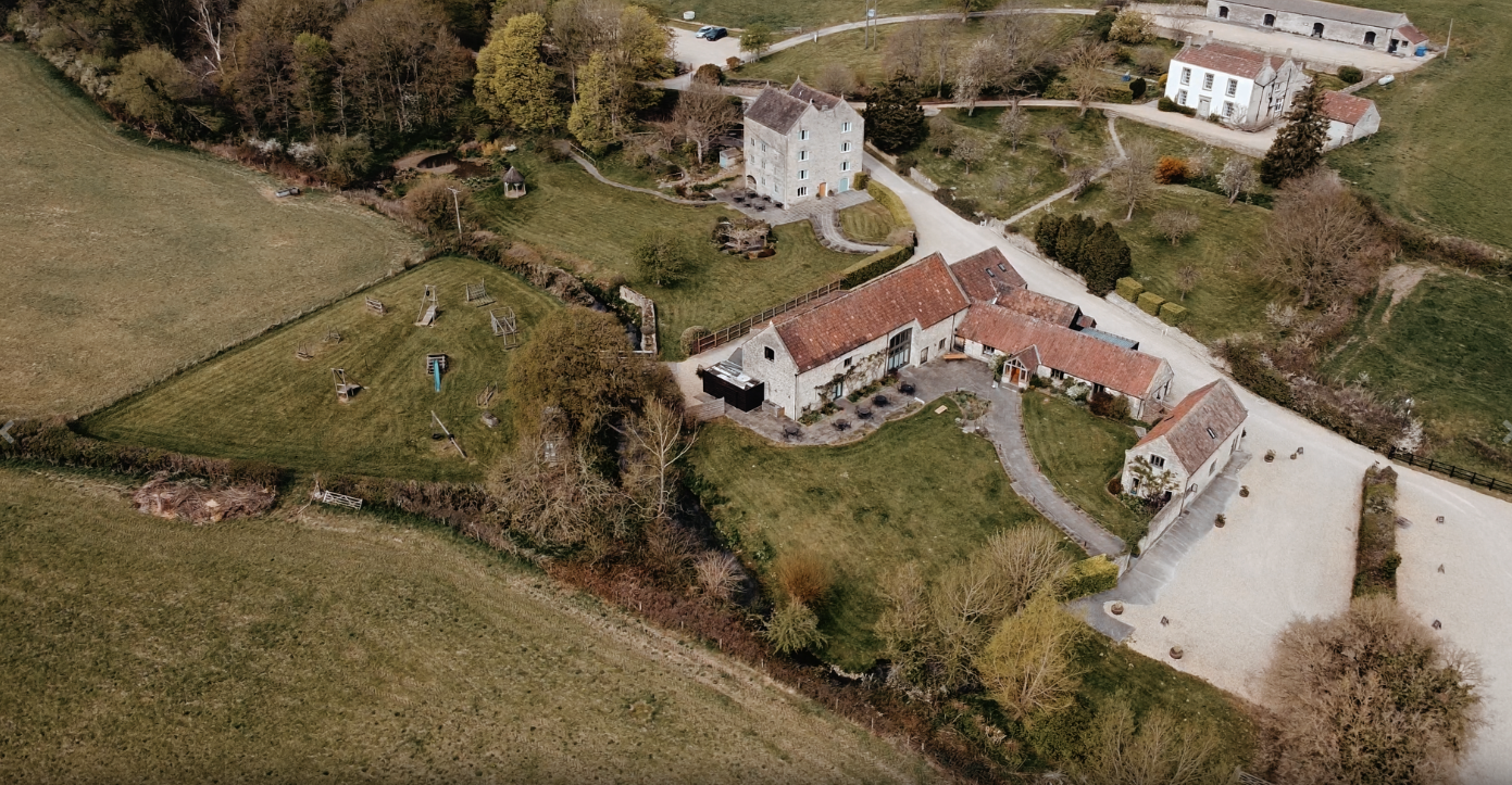 Aerial drone view of a wedding at Priston Mill, showcasing the historic venue and lush countryside setting.