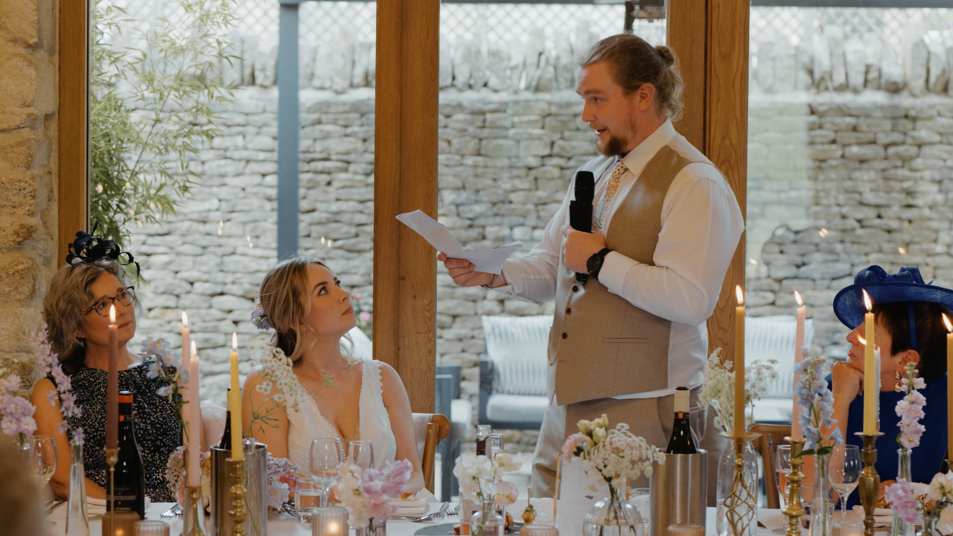 Best man giving a heartfelt speech to the bride and groom during the reception, a candid moment captured by a Somerset wedding videographer.