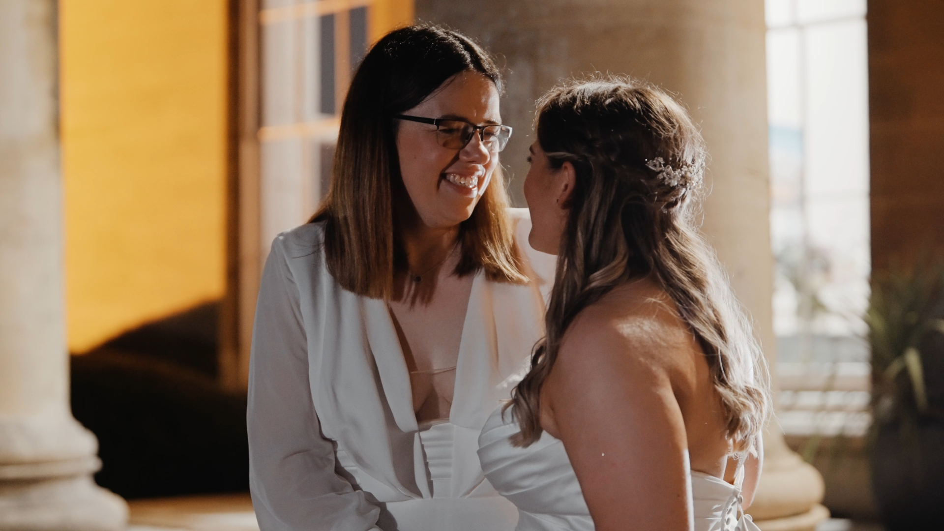 Two brides smiling at each other on their wedding day, beautifully captured for a wedding video package.