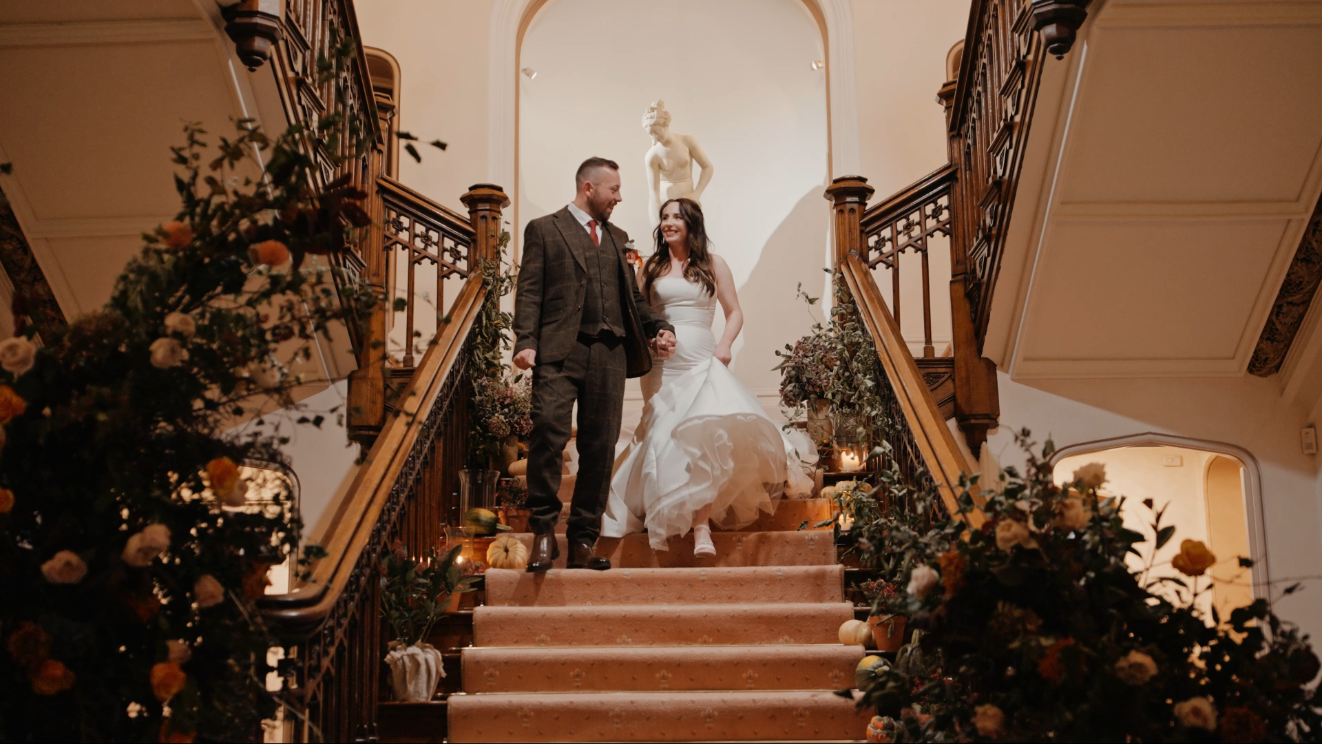 Bride and groom smiling as they enter the reception, walking down stairs during their autumn wedding celebration.