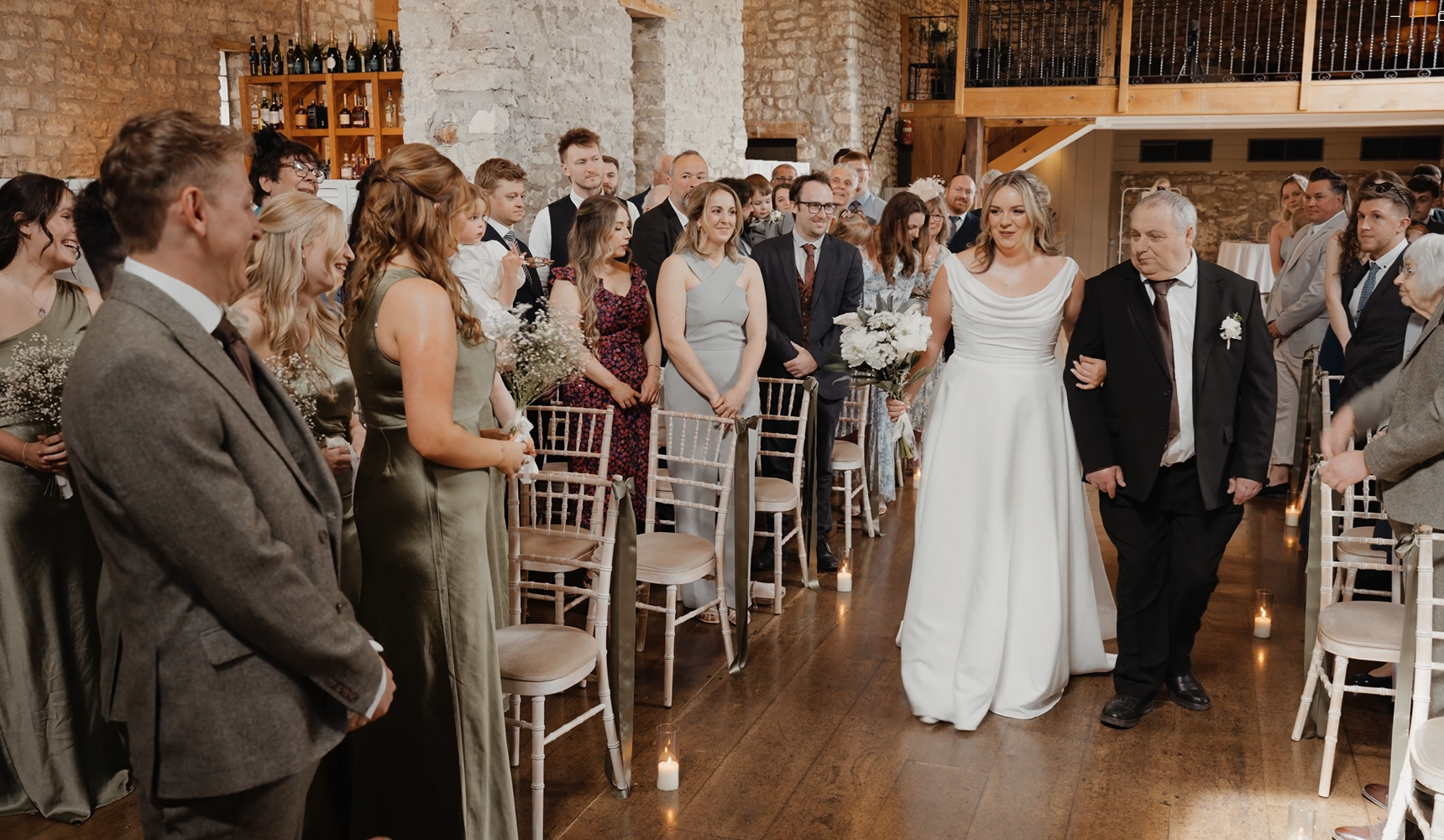 Bride smiling at her groom as he waits at the end of the aisle during their wedding at Priston Mill