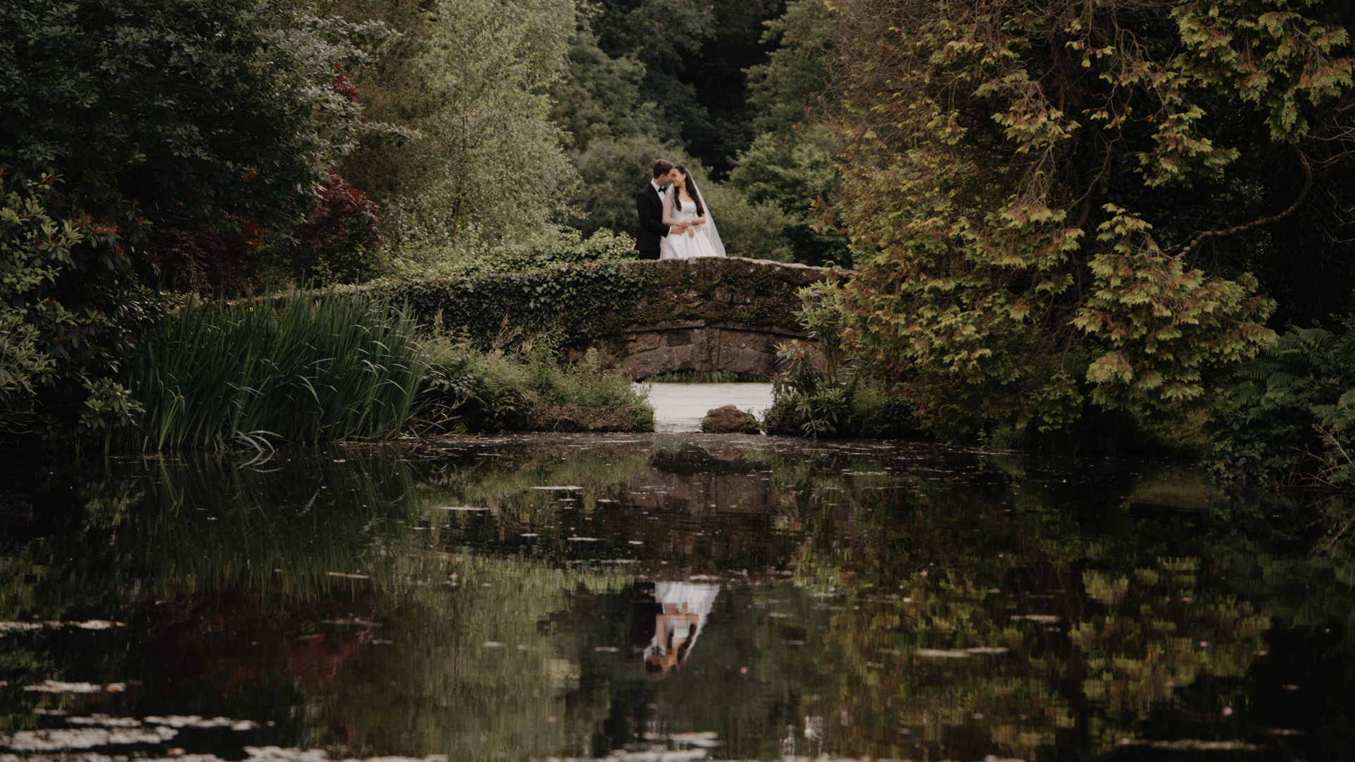 Bride and groom embrace by the lake