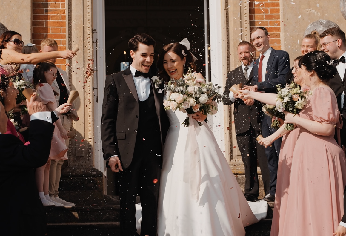 Bride and groom exit the ceremony while guests throw petals at them during their wedding day at Crowcombe court