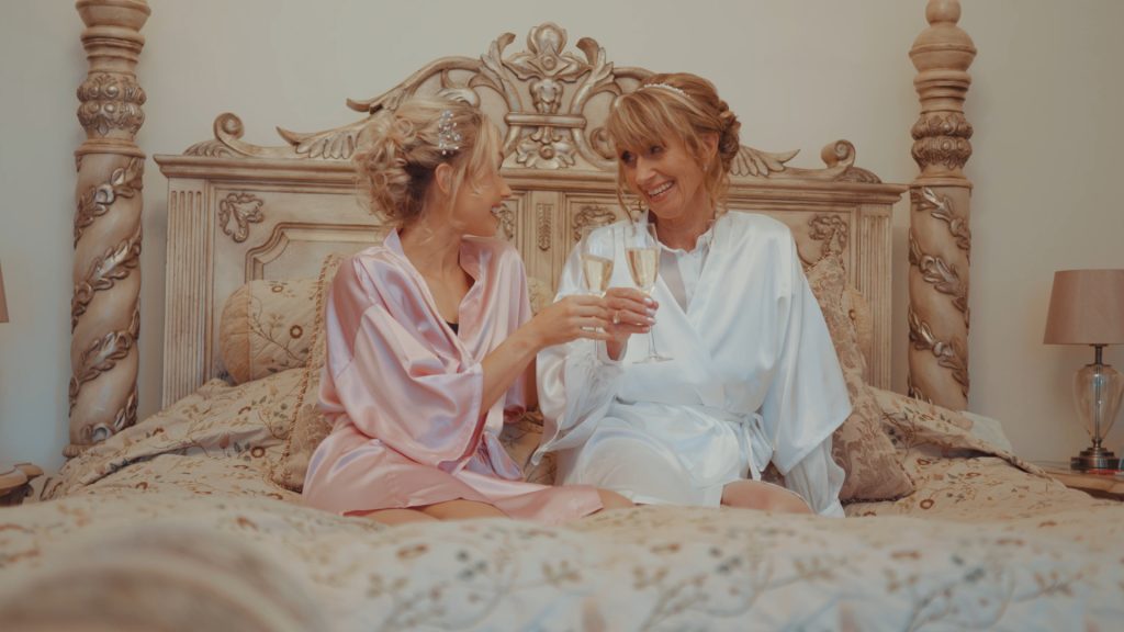 Bride shares a joyful champagne toast with her mother on the morning of bridal prep at Berwick Lodge, smiling warmly at each other in a tender moment.