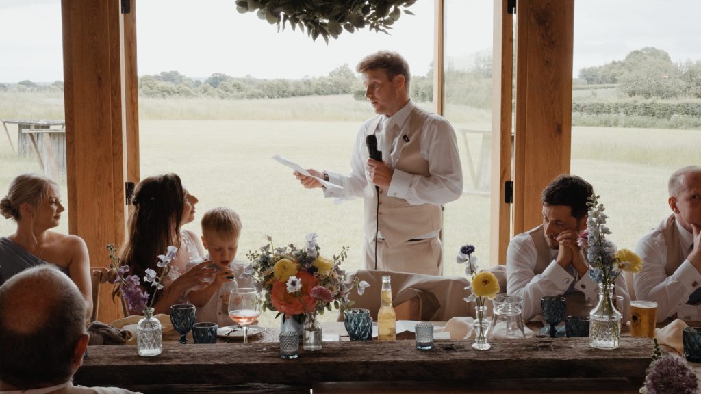 Groom giving a genuine and emotional wedding speech to his wife and son at Old Oak Farm, with guests listening closely to the touching moment.