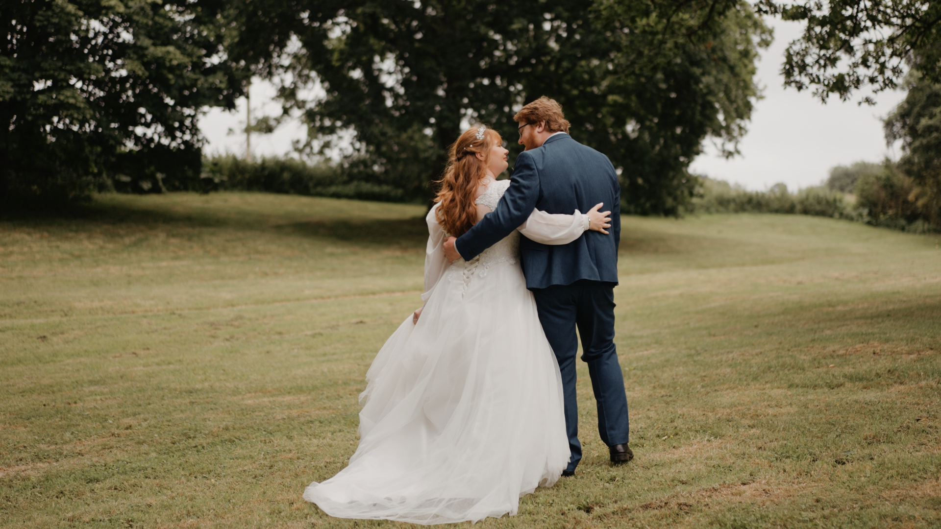 The bride and groom walking arm in arm through the lush summer gardens after their ceremony.