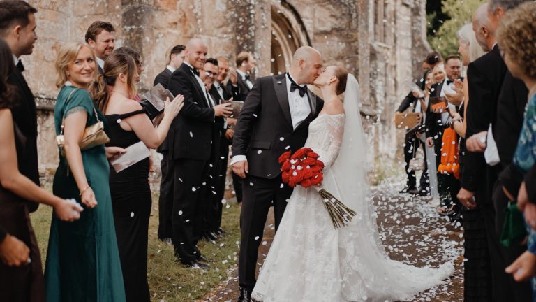 Bride and groom sharing a kiss under falling confetti, perfectly filmed for their wedding video package.