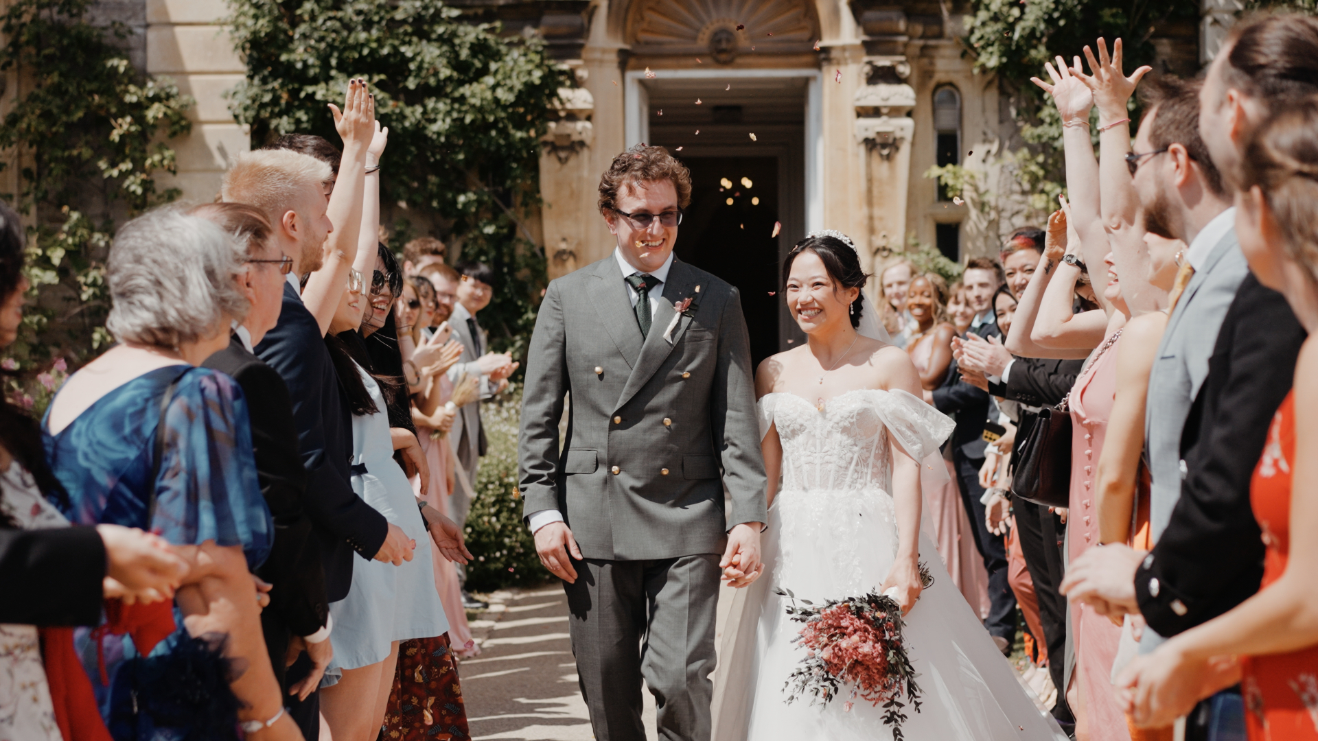 Bride and groom walking hand in hand during a joyful confetti exit at Clevedon Hall.