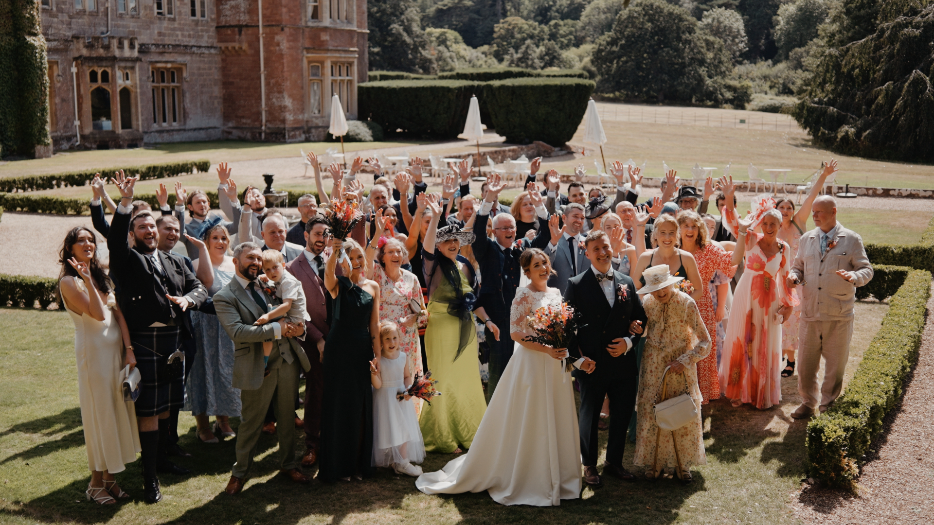 A joyful wedding group photo with the couple and their guests gathered on the lawns of St Audries Park.