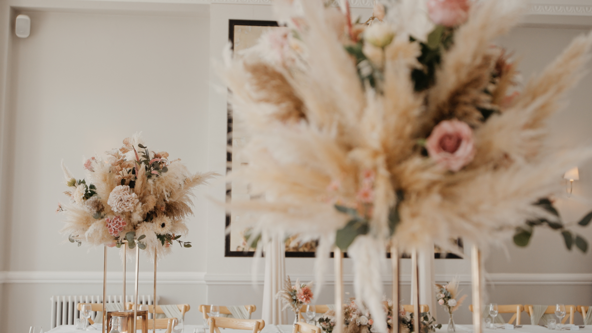 Boho wedding centrepieces with pampas grass and blush florals decorating the reception tables.