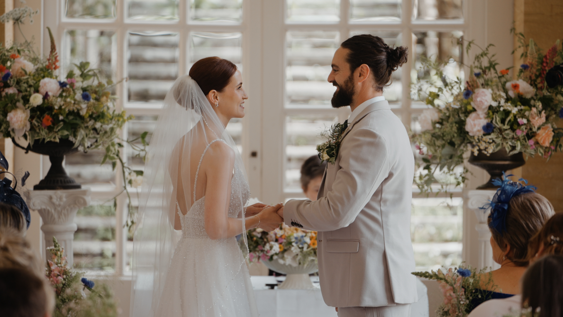 Laura and Kye hold hands and look at each other during their wedding ceremony in the beautiful Orangery.