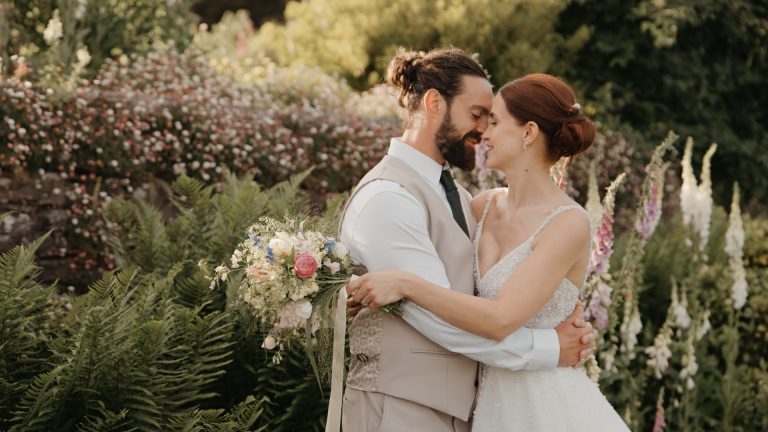 A romantic portrait of the bride and groom embracing in a lush garden at Hestercombe House & Gardens.