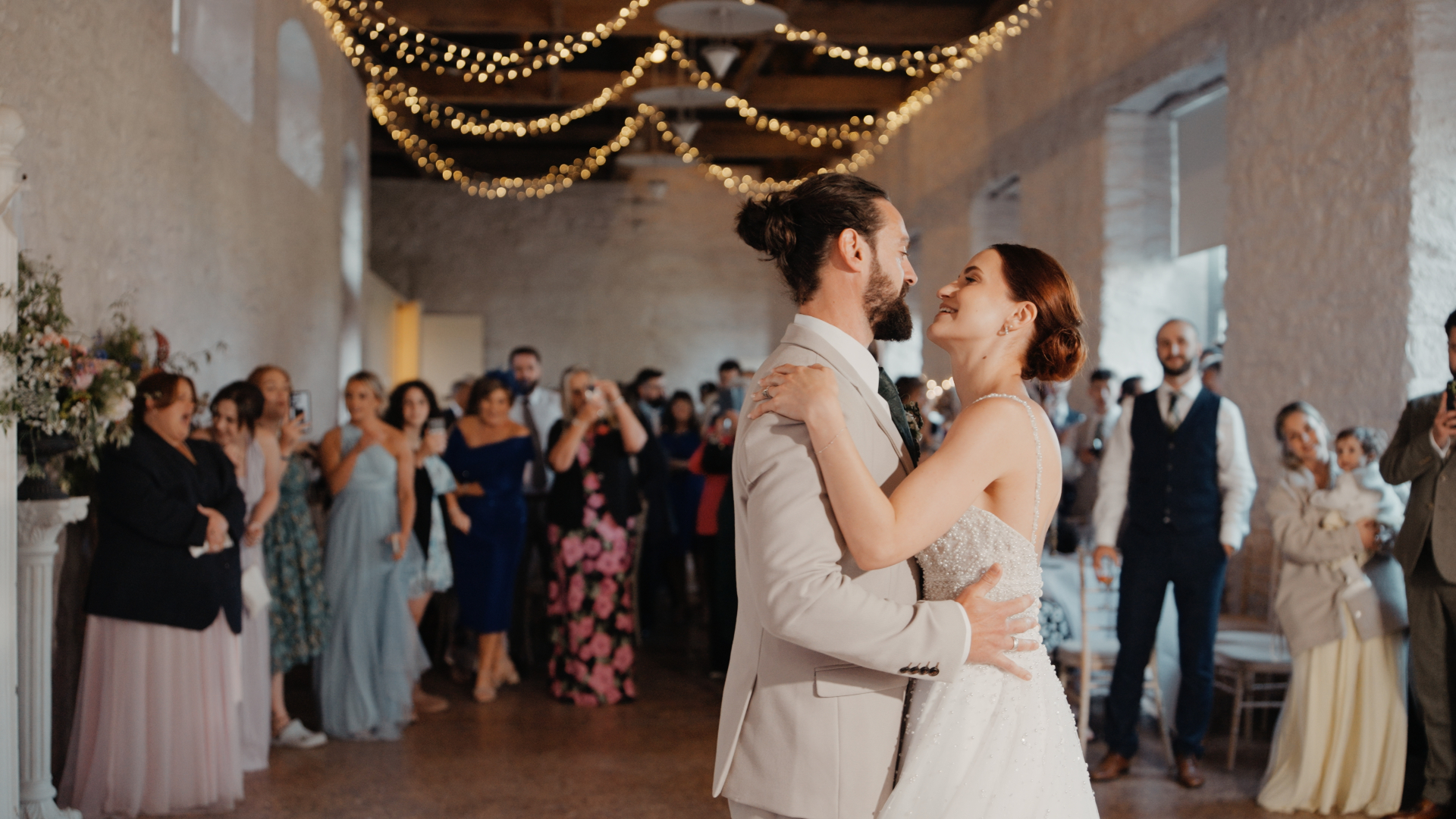 The bride and groom share their first dance, smiling at each other in the Bampfylde Hall at Hestercombe House & Gardens.