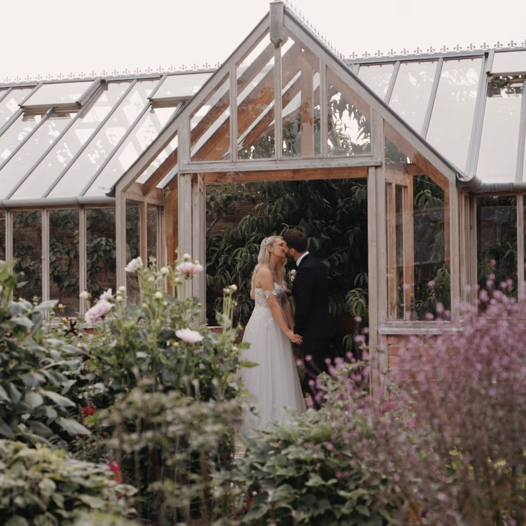 Bride and groom are facing each other in a walled garden orangery at Deer Park Country House.