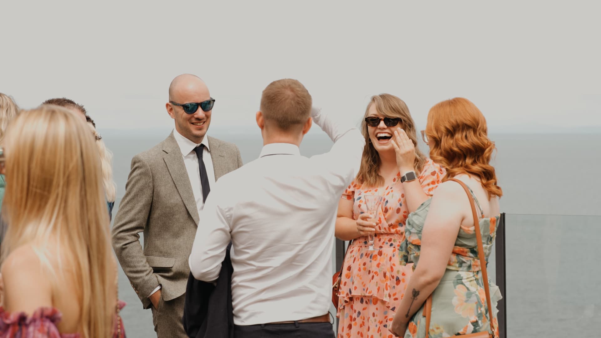 Guests laughing and chatting on the terrace, candidly filmed by a wedding videographer during the drinks reception.