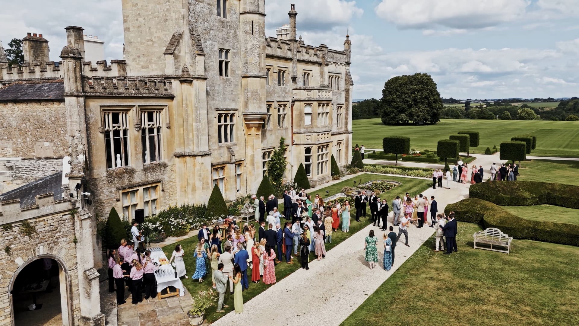 A breathtaking drone wedding videography shot of Farleigh House near Bath, capturing the newlyweds celebrating with family and friends on the elegant lawns.